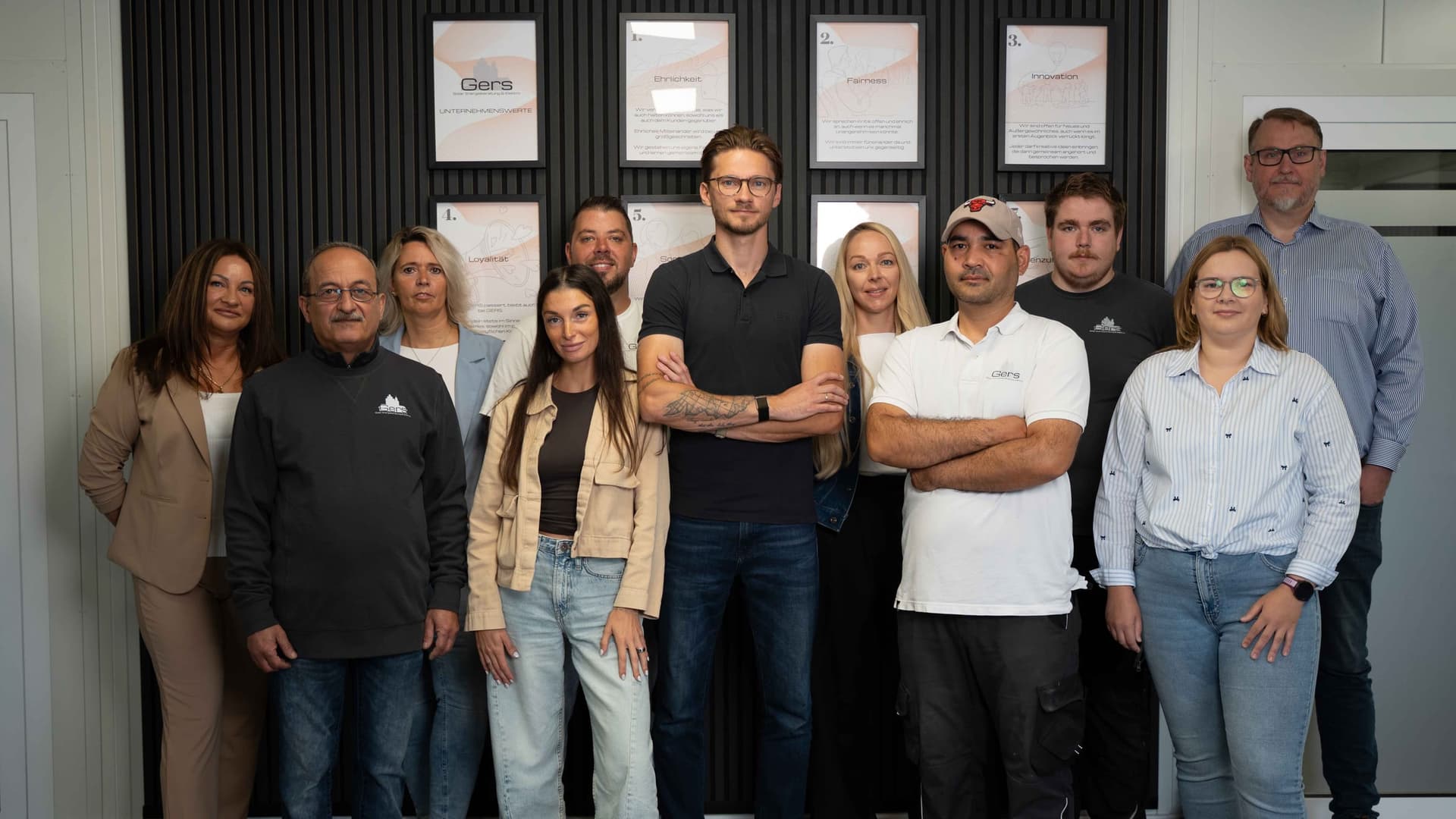Das Team von Gers Erneuerbare Energien vor der Wertewand im Firmengebaeude in Geeste